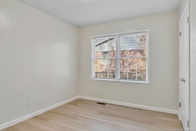 empty room with baseboards, visible vents, and light wood-style floors