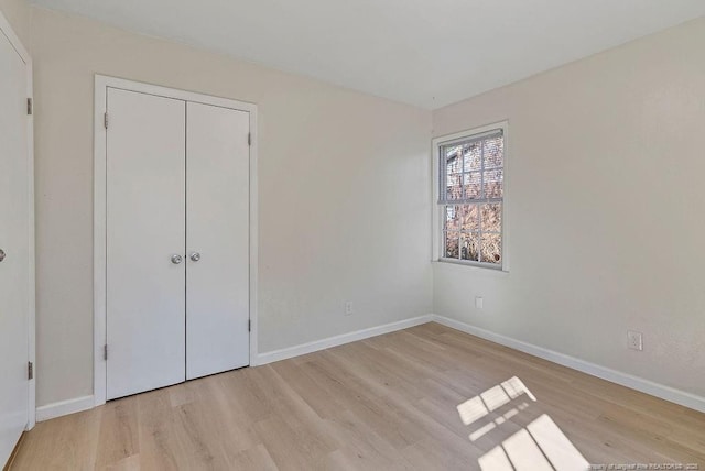 unfurnished bedroom featuring a closet, baseboards, and wood finished floors