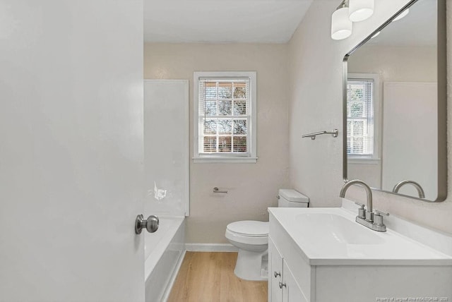 bathroom with vanity, wood finished floors, toilet, and baseboards