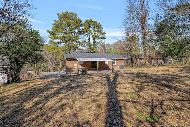 rear view of house featuring brick siding, a yard, and fence