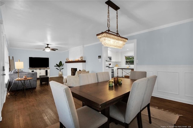 dining room with a fireplace, sink, dark hardwood / wood-style flooring, ceiling fan, and crown molding