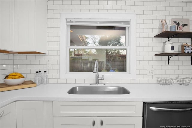 kitchen with dishwashing machine, sink, backsplash, and white cabinets