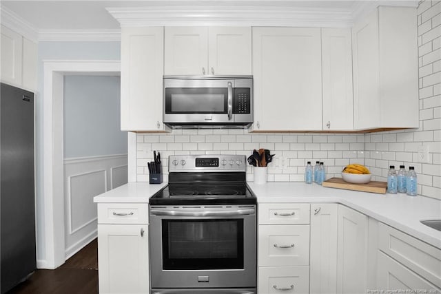 kitchen featuring ornamental molding, appliances with stainless steel finishes, and white cabinets