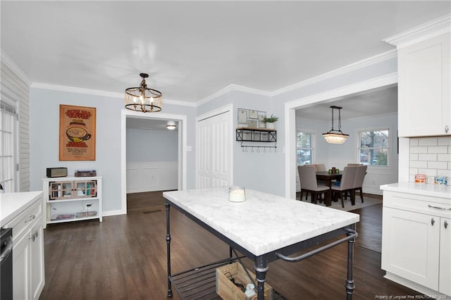 kitchen featuring dark wood-type flooring, a chandelier, hanging light fixtures, ornamental molding, and white cabinets