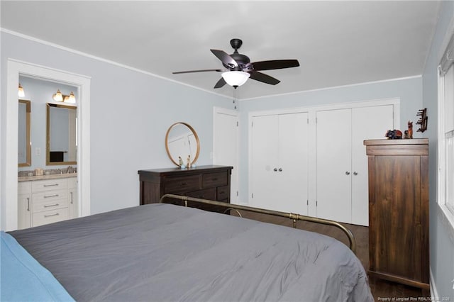 bedroom featuring ceiling fan, sink, two closets, and ensuite bath