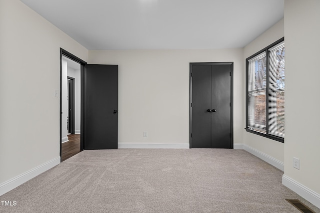 unfurnished bedroom with light colored carpet and a closet