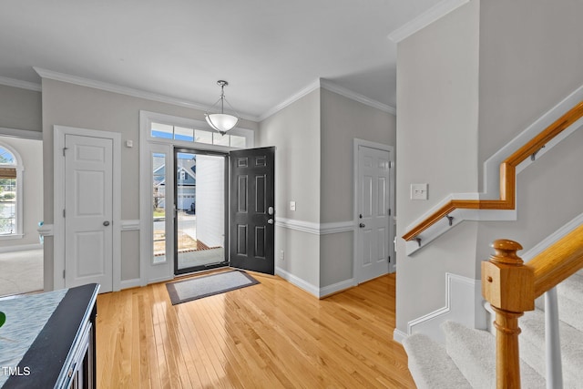 entryway with stairs, crown molding, light wood-type flooring, and baseboards