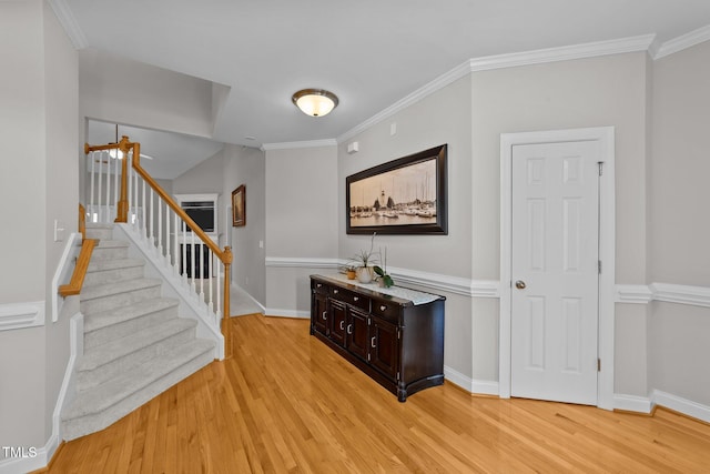 entrance foyer featuring baseboards, light wood finished floors, stairway, and crown molding