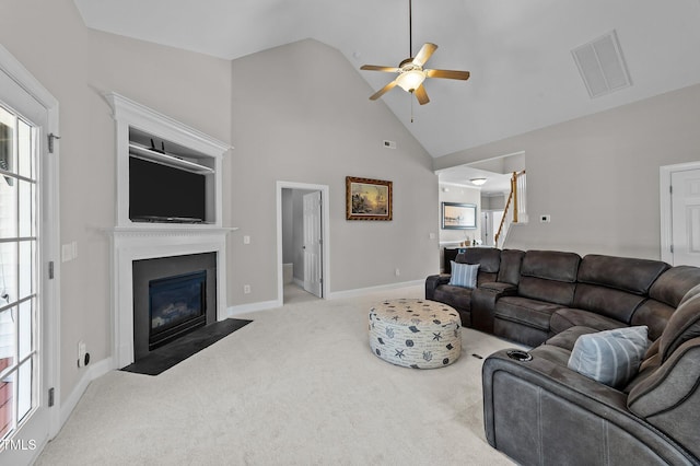 carpeted living room with ceiling fan, high vaulted ceiling, a fireplace with flush hearth, visible vents, and stairway