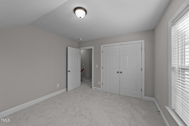 unfurnished bedroom with carpet floors, baseboards, a closet, and lofted ceiling