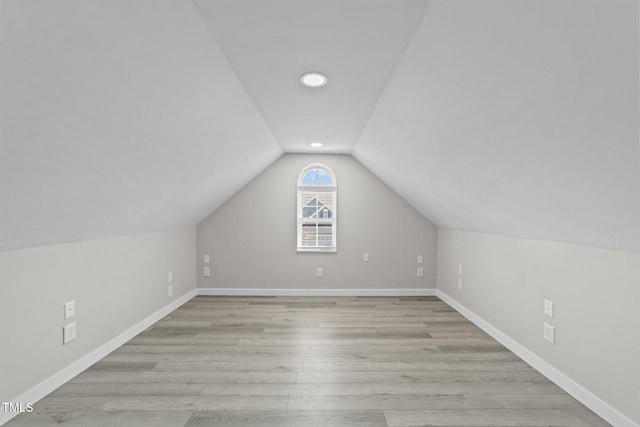 additional living space featuring light wood-style flooring, baseboards, and vaulted ceiling