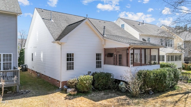 rear view of property featuring crawl space, a sunroom, a yard, and roof with shingles