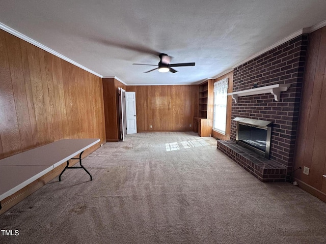 unfurnished living room with crown molding, light carpet, a textured ceiling, wooden walls, and a fireplace