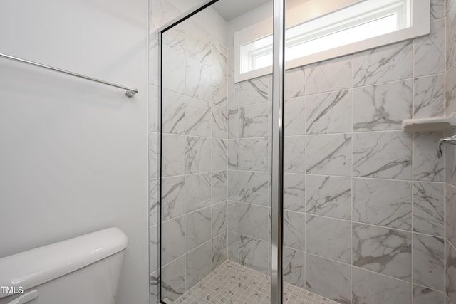 bathroom featuring tiled shower and toilet