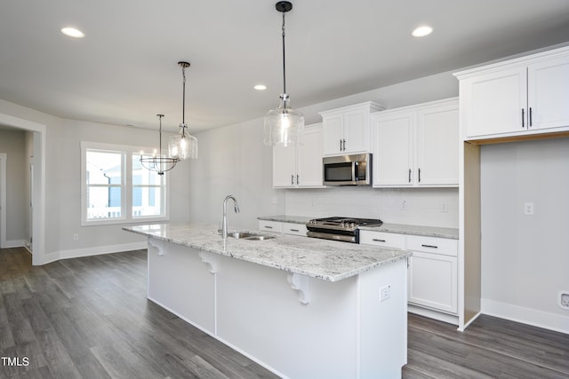 kitchen with pendant lighting, white cabinetry, an island with sink, sink, and stainless steel appliances