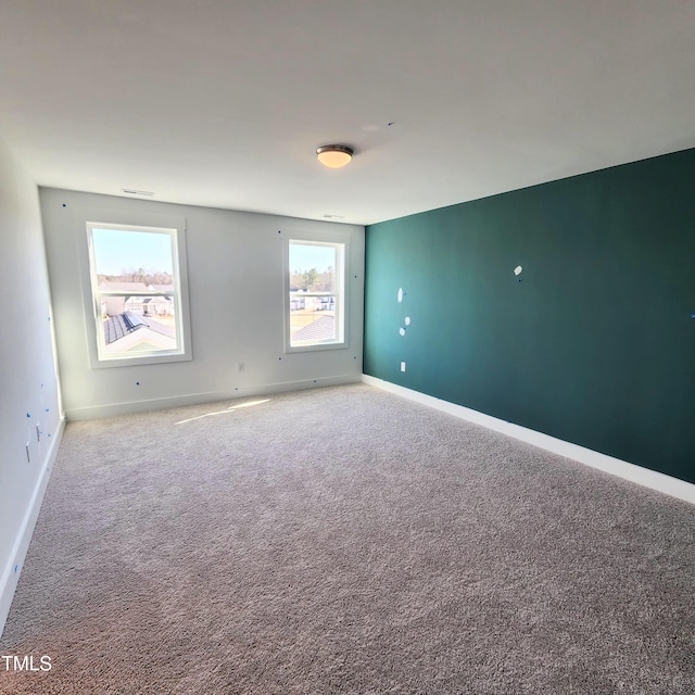 spare room featuring carpet flooring and baseboards