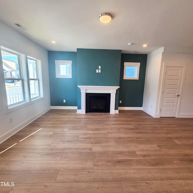 unfurnished living room with recessed lighting, visible vents, baseboards, and wood finished floors