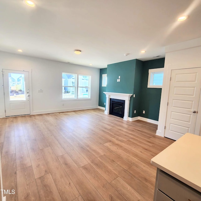 unfurnished living room featuring recessed lighting, baseboards, light wood-style floors, and a fireplace