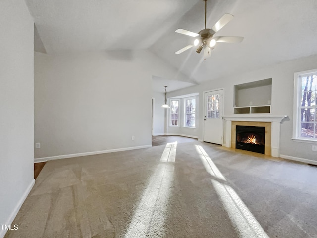 unfurnished living room with ceiling fan, lofted ceiling, plenty of natural light, and a tile fireplace