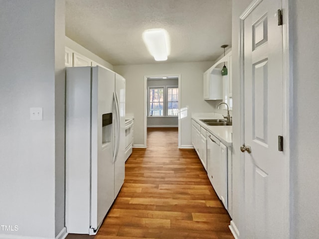 kitchen with sink, white cabinetry, light hardwood / wood-style flooring, a textured ceiling, and white appliances