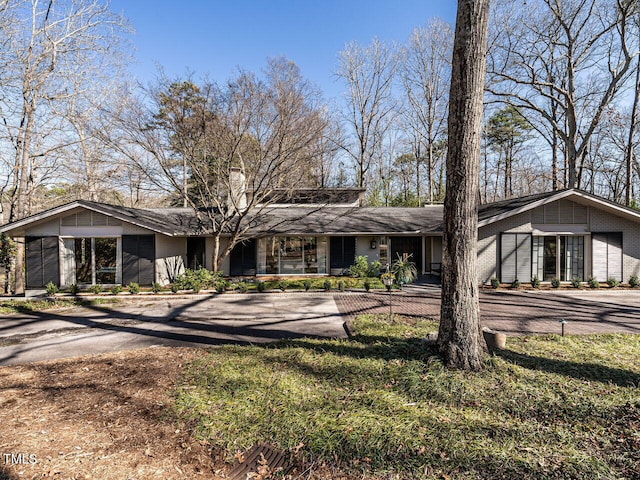 mid-century home with driveway, brick siding, and a front lawn