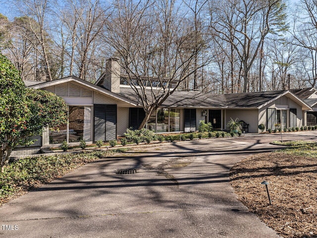 mid-century home with a chimney and brick siding