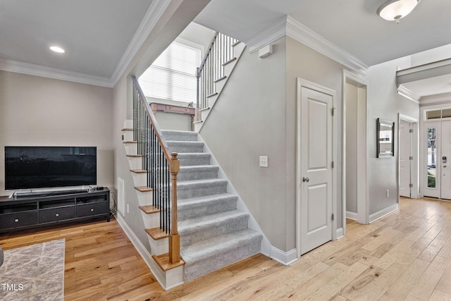 staircase with crown molding, a wealth of natural light, and hardwood / wood-style floors