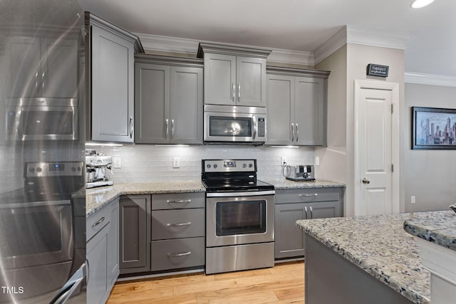 kitchen featuring stainless steel appliances, crown molding, gray cabinets, and backsplash