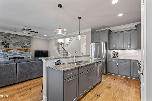 kitchen featuring appliances with stainless steel finishes, a kitchen bar, sink, and gray cabinetry