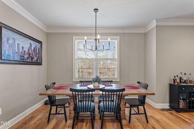 dining room with ornamental molding, an inviting chandelier, and light hardwood / wood-style flooring