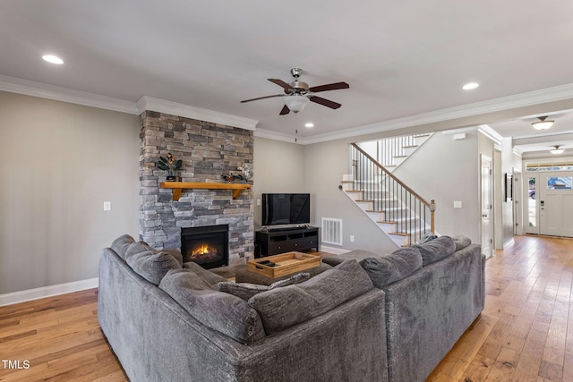 living room featuring a fireplace, ornamental molding, light hardwood / wood-style floors, and ceiling fan