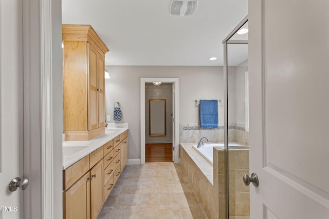 bathroom with a relaxing tiled tub and vanity