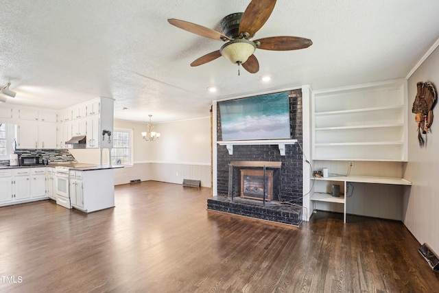 living room featuring ceiling fan with notable chandelier, a fireplace, a textured ceiling, and dark wood-style flooring