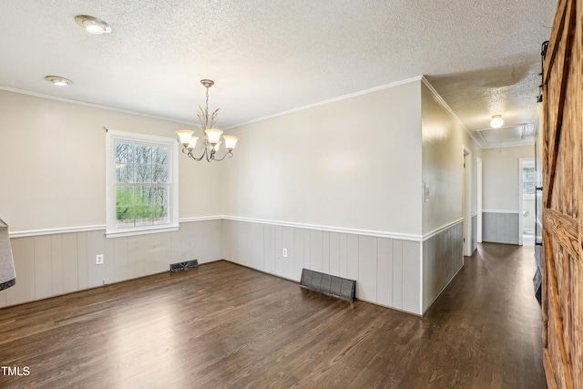 empty room with attic access, wood finished floors, a wainscoted wall, and a textured ceiling