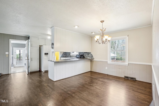 kitchen featuring visible vents, a notable chandelier, dark wood finished floors, white fridge with ice dispenser, and a peninsula