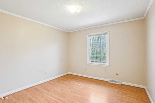 spare room with visible vents, baseboards, light wood-type flooring, ornamental molding, and a textured ceiling