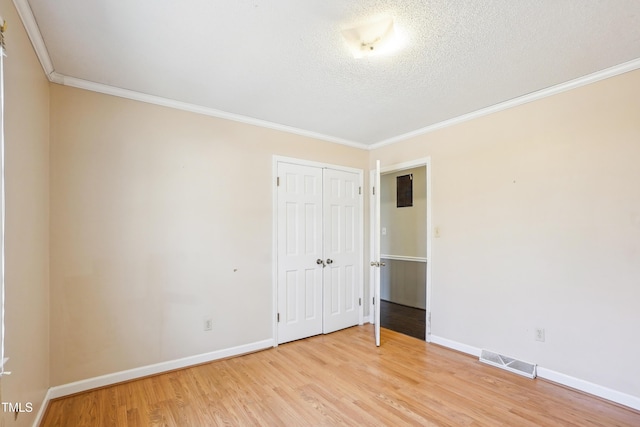 unfurnished bedroom with light wood-style flooring, baseboards, visible vents, and ornamental molding