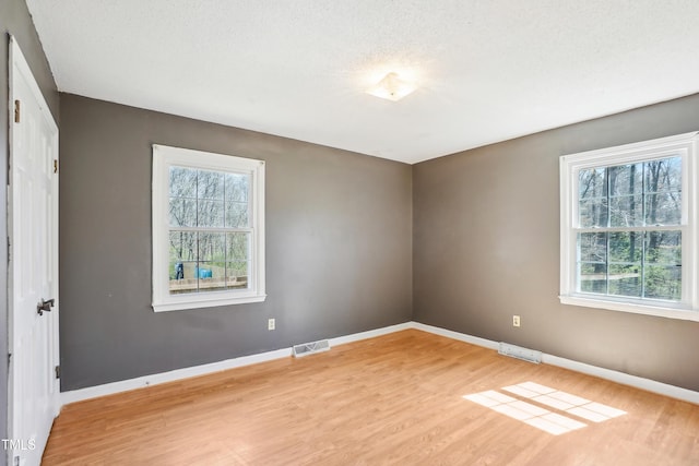unfurnished room with light wood-style flooring, baseboards, and visible vents