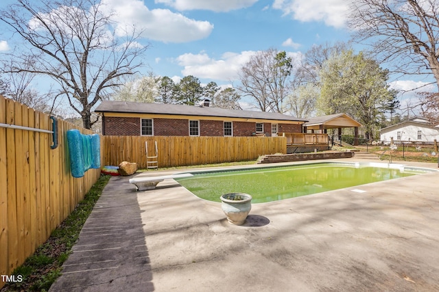 rear view of property with brick siding, a fenced in pool, a wooden deck, a fenced backyard, and a patio
