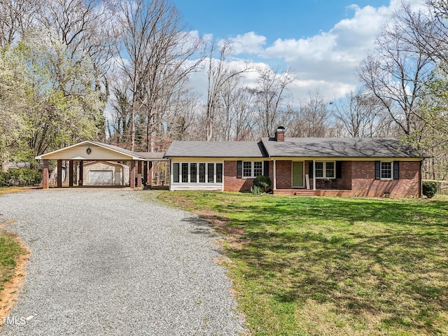 ranch-style home with brick siding, an attached carport, a front lawn, a chimney, and driveway