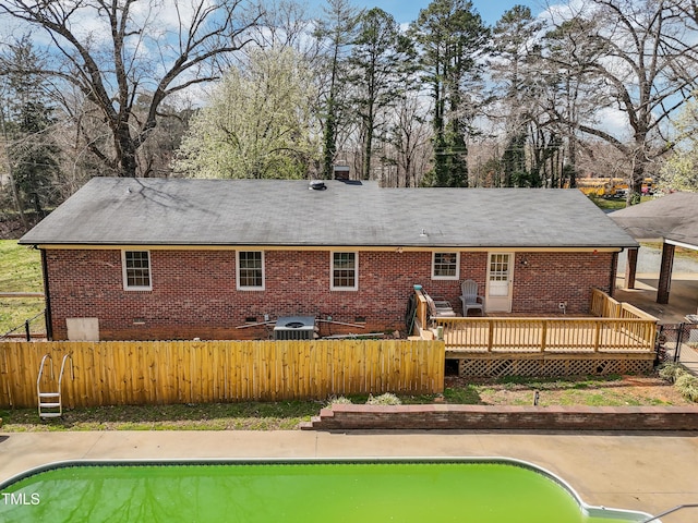 back of house featuring a fenced in pool, fence private yard, brick siding, and a wooden deck