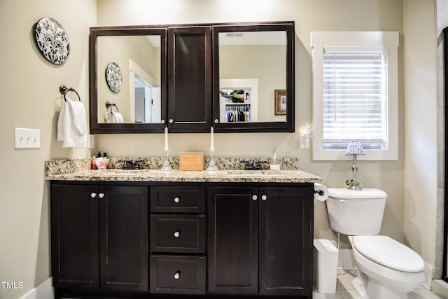 bathroom featuring toilet, double vanity, and a sink