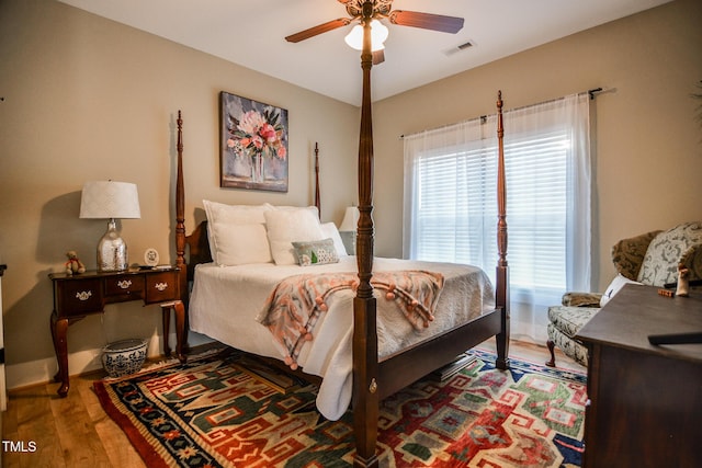 bedroom with ceiling fan, wood finished floors, visible vents, and baseboards