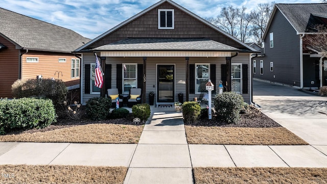 bungalow with covered porch and a shingled roof