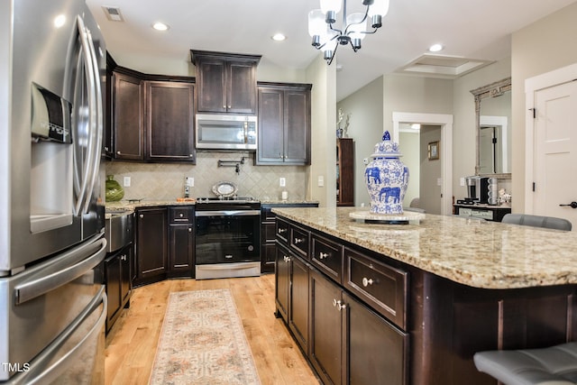 kitchen with tasteful backsplash, visible vents, appliances with stainless steel finishes, light stone countertops, and light wood-type flooring