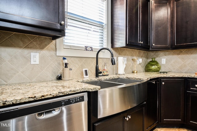 kitchen with dishwasher, tasteful backsplash, a sink, and light stone countertops