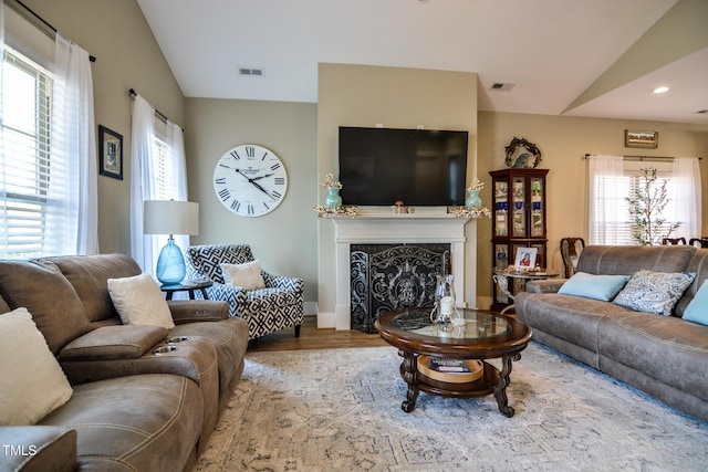 living room featuring lofted ceiling, recessed lighting, a premium fireplace, wood finished floors, and visible vents