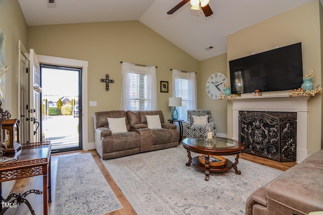 living area featuring visible vents, a ceiling fan, wood finished floors, vaulted ceiling, and a high end fireplace