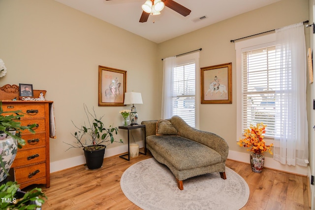 living area with baseboards, light wood-style flooring, visible vents, and a ceiling fan