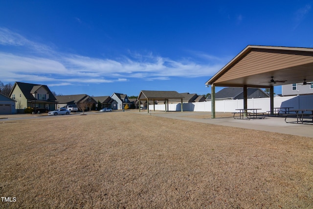 view of yard featuring ceiling fan, a residential view, fence, and a patio